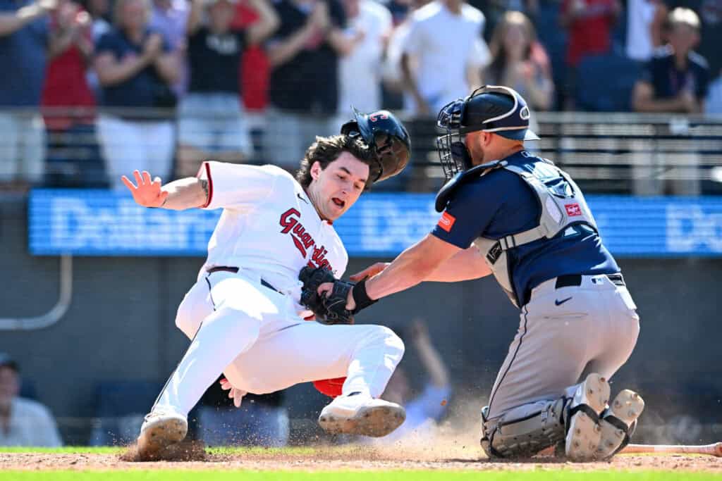 CLEVELAND, OHIO - JUNE 28: Chase DeLauter #24 of the Cleveland Guardians avoids the tag by Mitch Garver #18 of the Seattle Mariners at home plate to score on a two-run double hit by Rhys Hoskins during the eighth inning at Progressive Field on June 28, 2026 in Cleveland, Ohio.