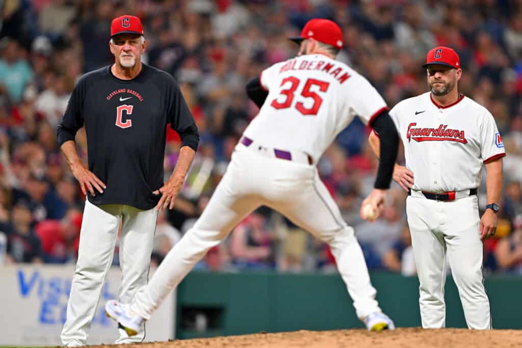 CLEVELAND, OHIO - AUGUST 15: Pitching coach Carl Willis #51 and manager Stephen Vogt #12 of the Cleveland Guardians watch relief pitcher Colin Holderman #35 after an apparent injury during the seventh inning against the San Diego Padres at Progressive Field on August 15, 2026, in Clevel
